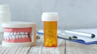  Plastik diş modeli ve tıbbi haplar masanın üstünde. 