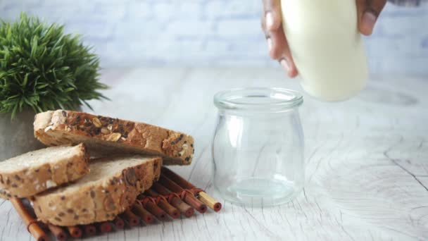 Verser du lait dans le verre sur la table — Video