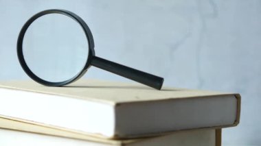 Masada bir yığın kitap ve büyüteç var. 