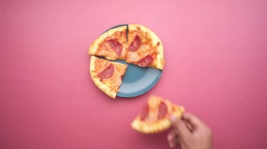 Bir tabaktan pizza seçen bir adamın üst görüntüsü. 