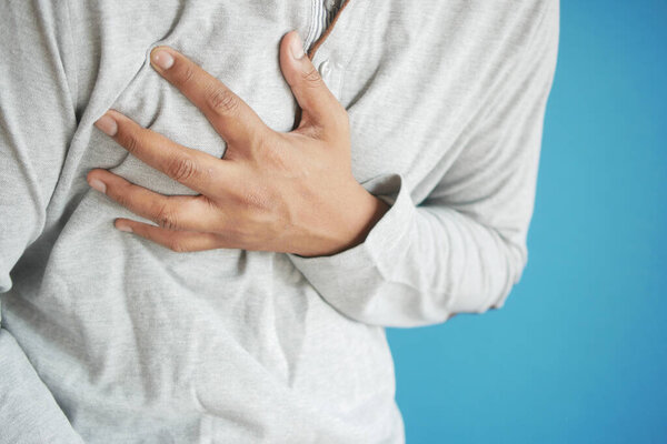 young man suffering pain in heart and holding chest with hand 