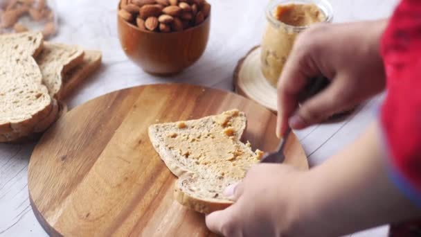 Beurre d'amande tartiné sur un pain brun sur la table — Video