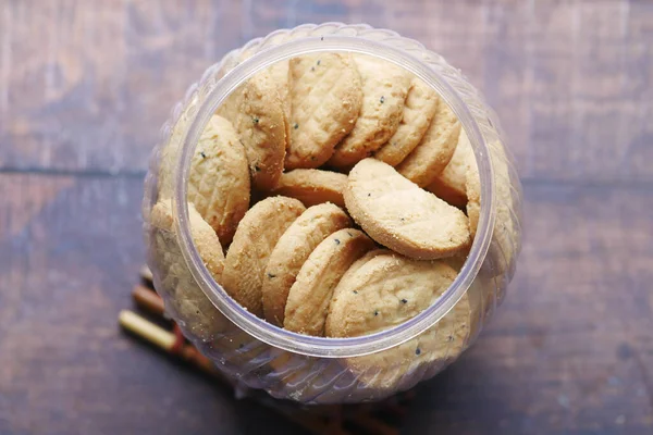 Perto de biscoitos doces em um jarro plástico na mesa de madeira — Fotografia de Stock