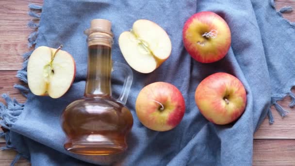 Vinagre de manzana en botella de vidrio con manzana verde fresca en la mesa — Vídeos de Stock