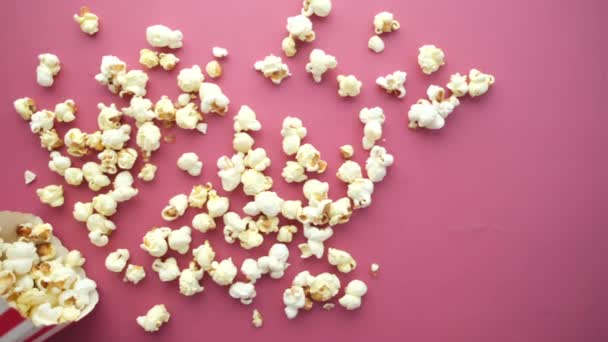 Popcorn spilling from a paper container on red background — Stock Video