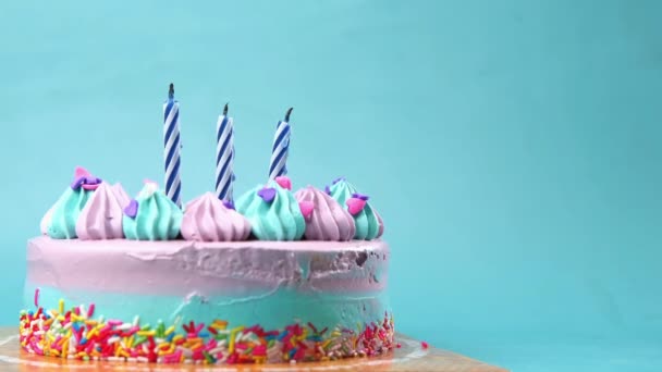 Câmera lenta de queimar vela em um bolo de aniversário no fundo roxo claro — Vídeo de Stock