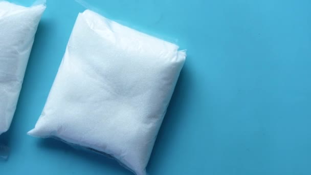 Білий цукор в пакеті на синьому фоні — стокове відео