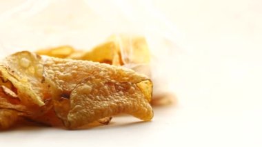 Patates cipsi beyaz arka planda bir paketten dökülüyor 