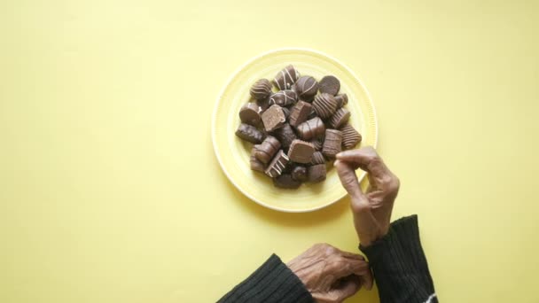 Las mujeres mayores recogen a mano el chocolate negro en un plato — Vídeos de Stock