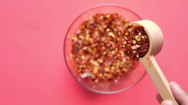 Zeitlupe des Gießens roter Chiliflocken in einem Löffel Nahaufnahme — Stockvideo