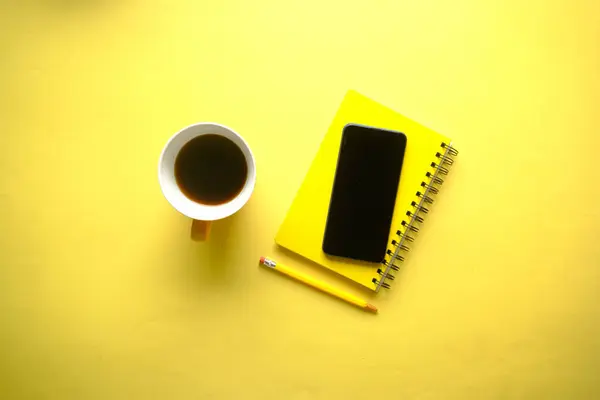 Top view of smart phone and notepad on yellow — Stock Photo, Image