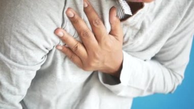 Genç adam kalp ağrısı çekiyor ve göğsünü eliyle tutuyor. 