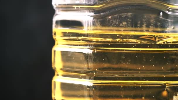 Cámara lenta de botella de aceite de girasol amarillo contra color negro — Vídeo de stock
