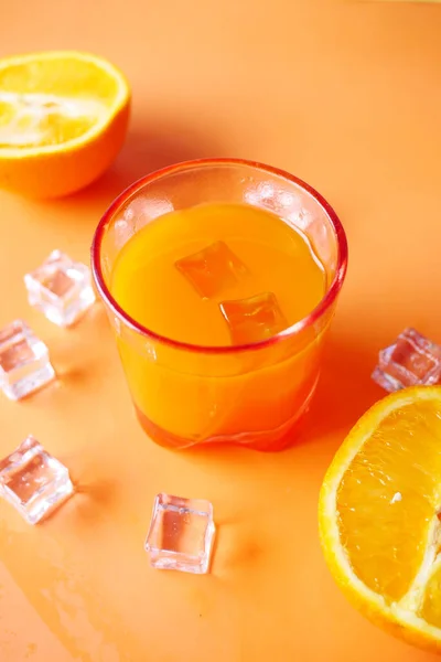 Vista superior de un vaso de jugo de naranja con hielo sobre fondo de color — Foto de Stock