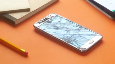 Turuncu arka planda kırık akıllı telefonu tutan adam. 