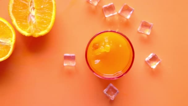 Top view of a glass of orange juice with ice on color background — 비디오