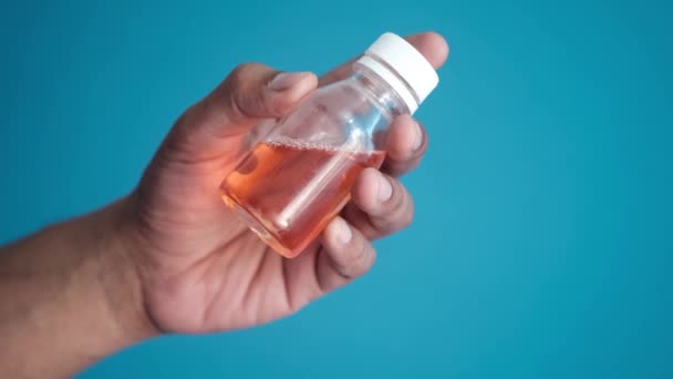 Hålla flaska med flytande läkemedel på blå bakgrund — Stockvideo