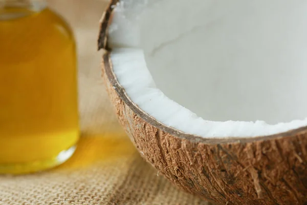 Parte de coco fresco e garrafa de óleo em uma mesa — Fotografia de Stock