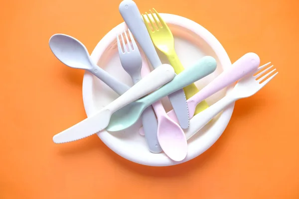Placas plásticas coloridas, vidro e talheres na mesa — Fotografia de Stock