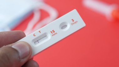  Kırmızı arkaplanda negatif Covid-19 test kiti tutuluyor 