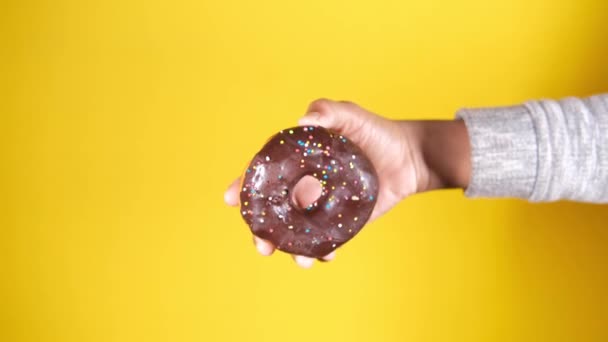 Рука тримає свіжі пончики на жовтому фоні — стокове відео