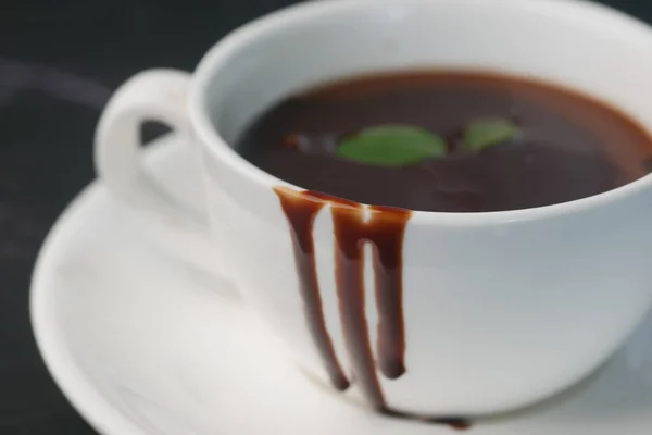 Crema de chocolate negro en una taza de café en la mesa — Foto de Stock