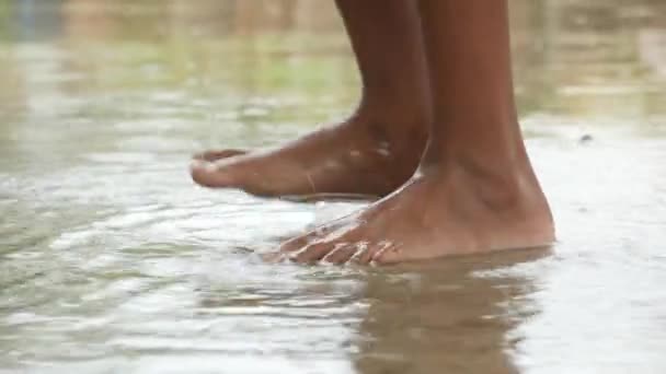 Kind springt op water water na regen — Stockvideo