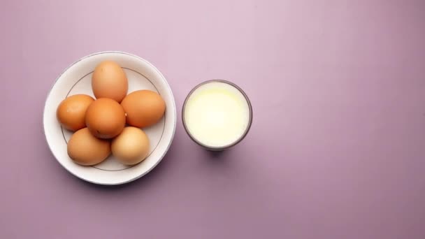 Яйца в луке и стакан молока на столе — стоковое видео