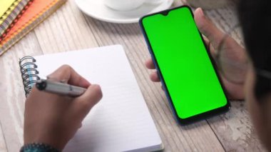 Ofis masasında akıllı telefon kullanan bir adamın üst görüntüsü. 