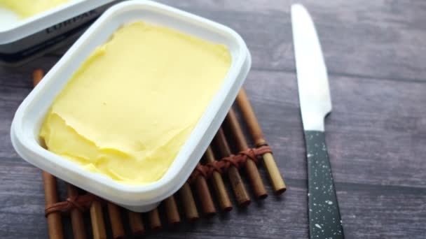 Verse boter in een container met brood op witte achtergrond — Stockvideo
