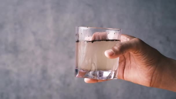 Holding dirty glass of water against black background — ストック動画