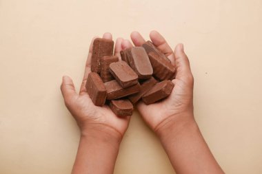 teenage boy holding many candy bar on table ,