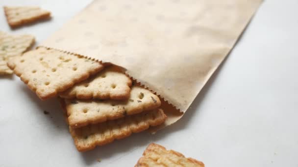 Perto de biscoitos doces que se derramam de um pacote de papel no branco — Vídeo de Stock