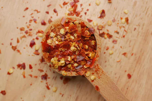Red chili pepper flakes in wooden spoon — Foto de Stock