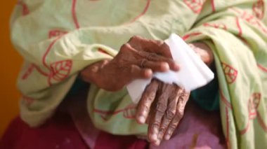 Yaşlı kadınlar ellerini ıslak mendille dezenfekte ediyor..