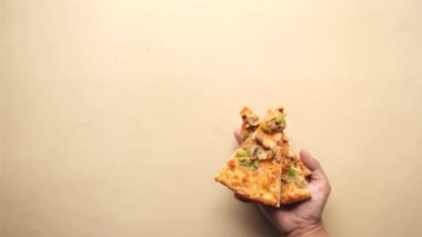 Bir tabaktan pizza seçen bir adamın üst görüntüsü. 