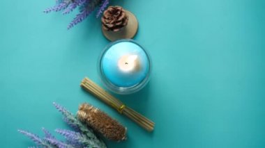 Cam bir kavanozda doğal mum ve mavi üzerinde kurumuş çiçekler. 