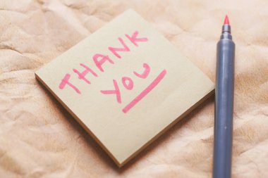 thank you message on a sticky note on old paper 