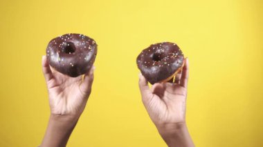 Sarı arka planda taze çörekleri tutan el. 