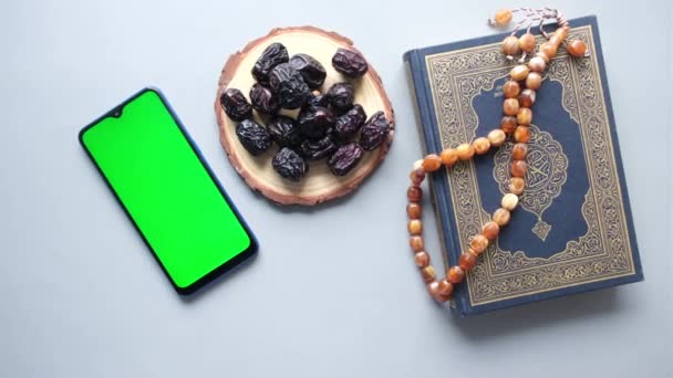 Telefone inteligente, livro sagrado Alcorão e rosário na mesa, — Vídeo de Stock