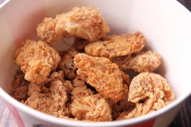 Masadaki kağıt pakette kızarmış tavuk kanadı. 