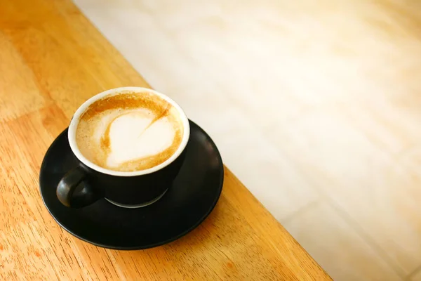Šálek pozdní kávy s květinovým vzorem navrchu v kavárně — Stock fotografie