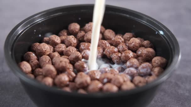 Slow motion of pouring milk in a chocolate corn flakes in a bowl — Stockvideo