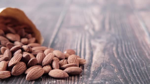 Almond nuts spilling from a paper packet on table — Vídeo de Stock