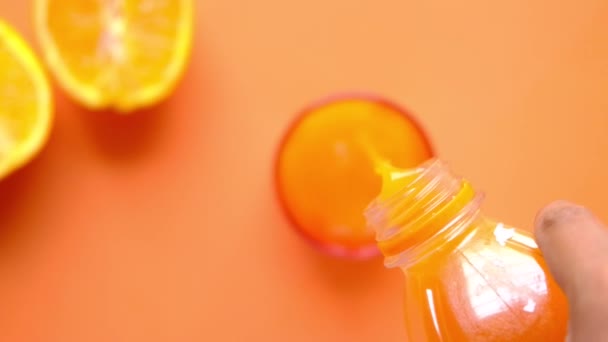 Verser du jus d'orange dans un verre sur un fond de couleur — Video