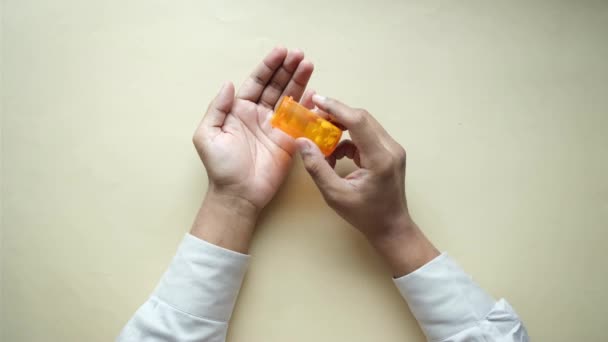 Mão de homem com medicamento derramado para fora do recipiente da pílula — Vídeo de Stock