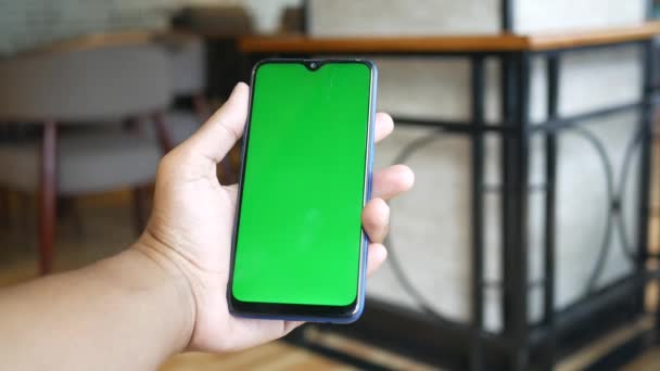 Mano de hombre joven utilizando el teléfono inteligente con pantalla verde en la cafetería — Vídeo de stock