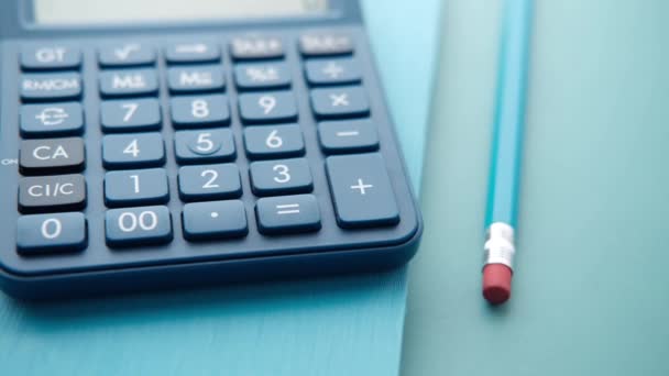 Close-up de calculadora azul e bloco de notas sobre fundo de cor — Vídeo de Stock