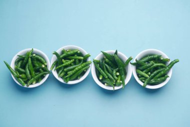 top view of green chili in a white bowl on table 