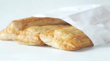 close up of apple pie cake in a paper packet on white 